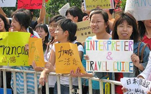 Mulheres buscam quem queira serviços de tradução em feira, na China. (Foto: AP)